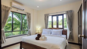 A hotel room with a large bed, two windows with curtains, an air conditioning unit, and a nightstand with a lamp. - First Private Pool Villa, 4-bedroom private pool villa in peaceful Ao Nang, (Ao Nang)
