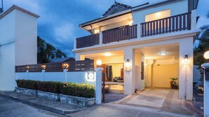 A two-story house with a balcony, a well-lit entrance, and a small garden area. - First Private Pool Villa, 4-bedroom private pool villa in peaceful Ao Nang, (Ao Nang)