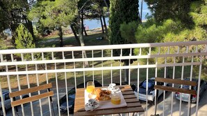 Un balcon avec une table préparée pour le petit-déjeuner, donnant sur un parc et un plan d’eau.