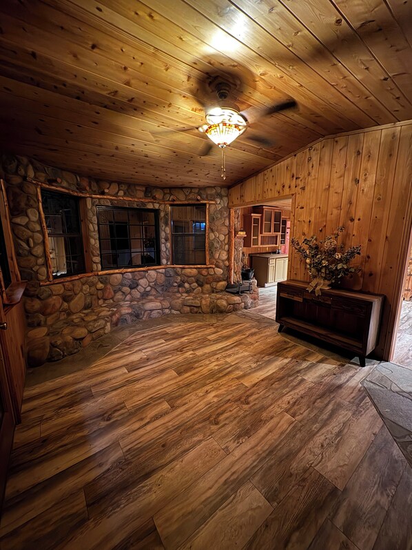 Una habitación amplia con paredes de madera y una chimenea de piedra.