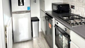 A compact kitchen with a stainless steel refrigerator, a microwave, a stove, and a dishwasher. - Freshly Renovated 2 bed Near City Airport (London)