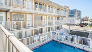 A multi-story hotel with balconies, a swimming pool, and a view of the city.