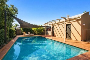A swimming pool with a wooden deck, a pergola, and a covered area with lounge chairs. - Mountain Views & Pool | 2BR Peaceful Kelvin Grove (Brisbane)