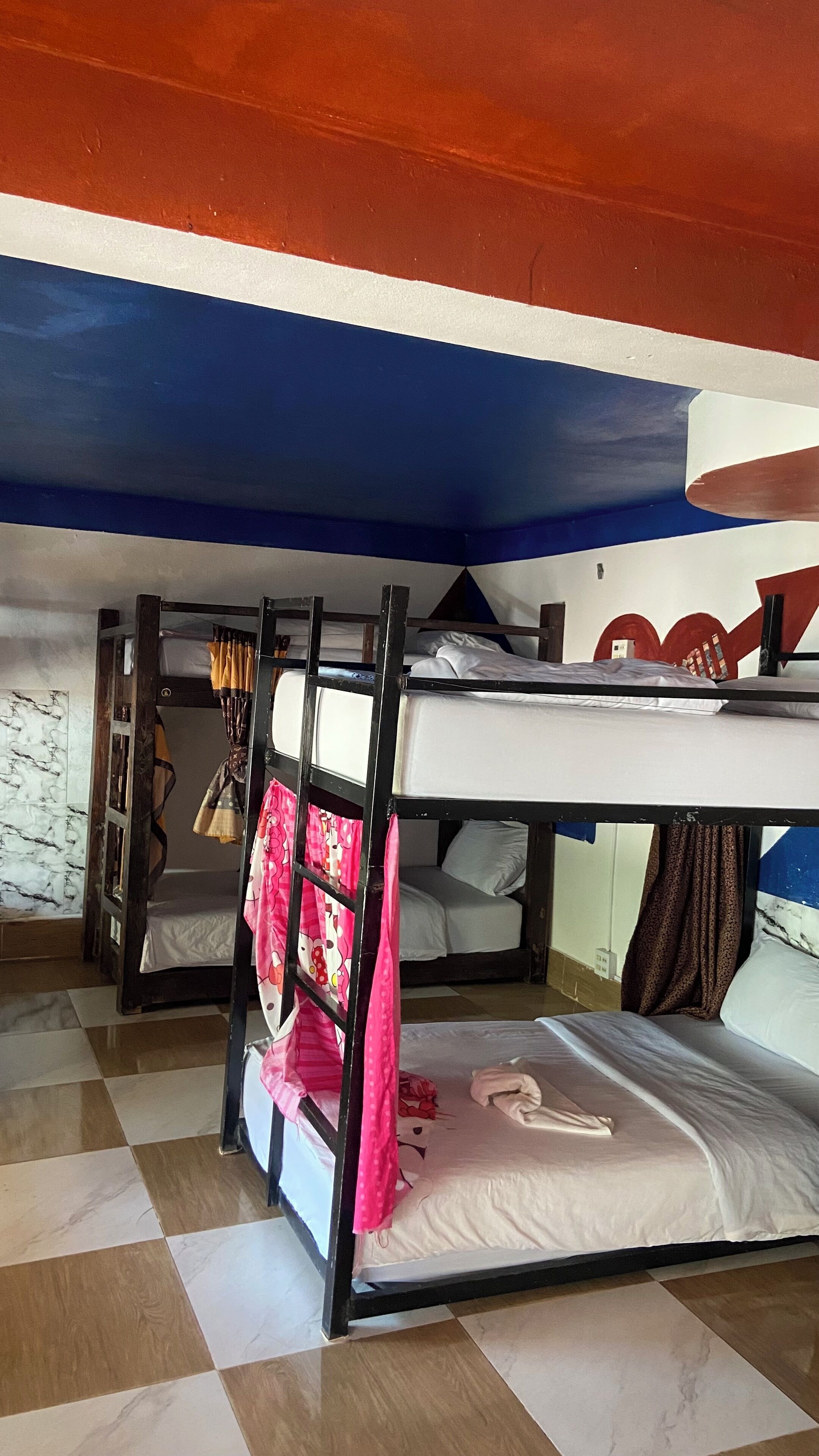 Un dormitorio con literas, suelo de cuadros y techo pintado.
