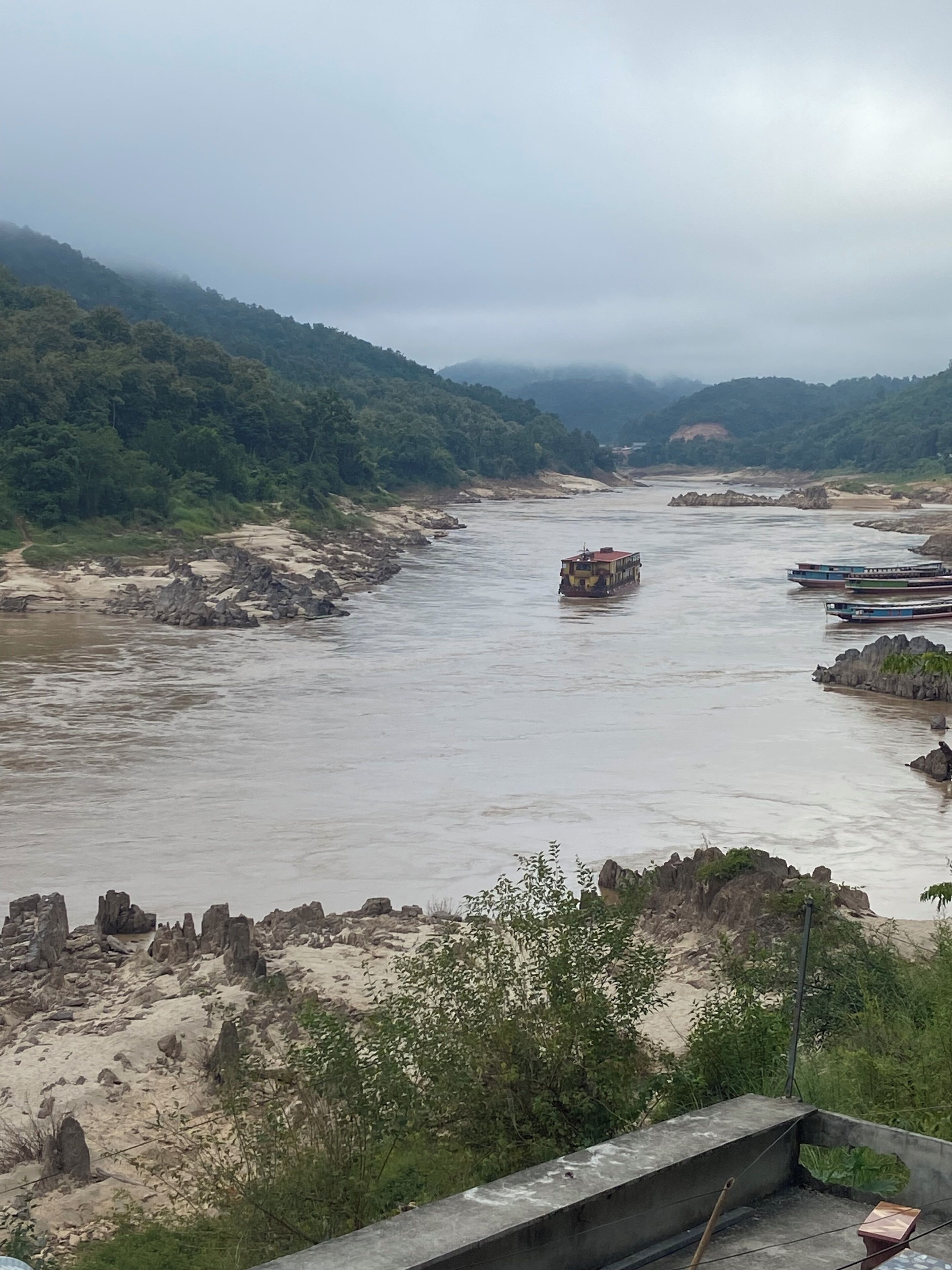 A river with boats, rocky banks, and greenery.