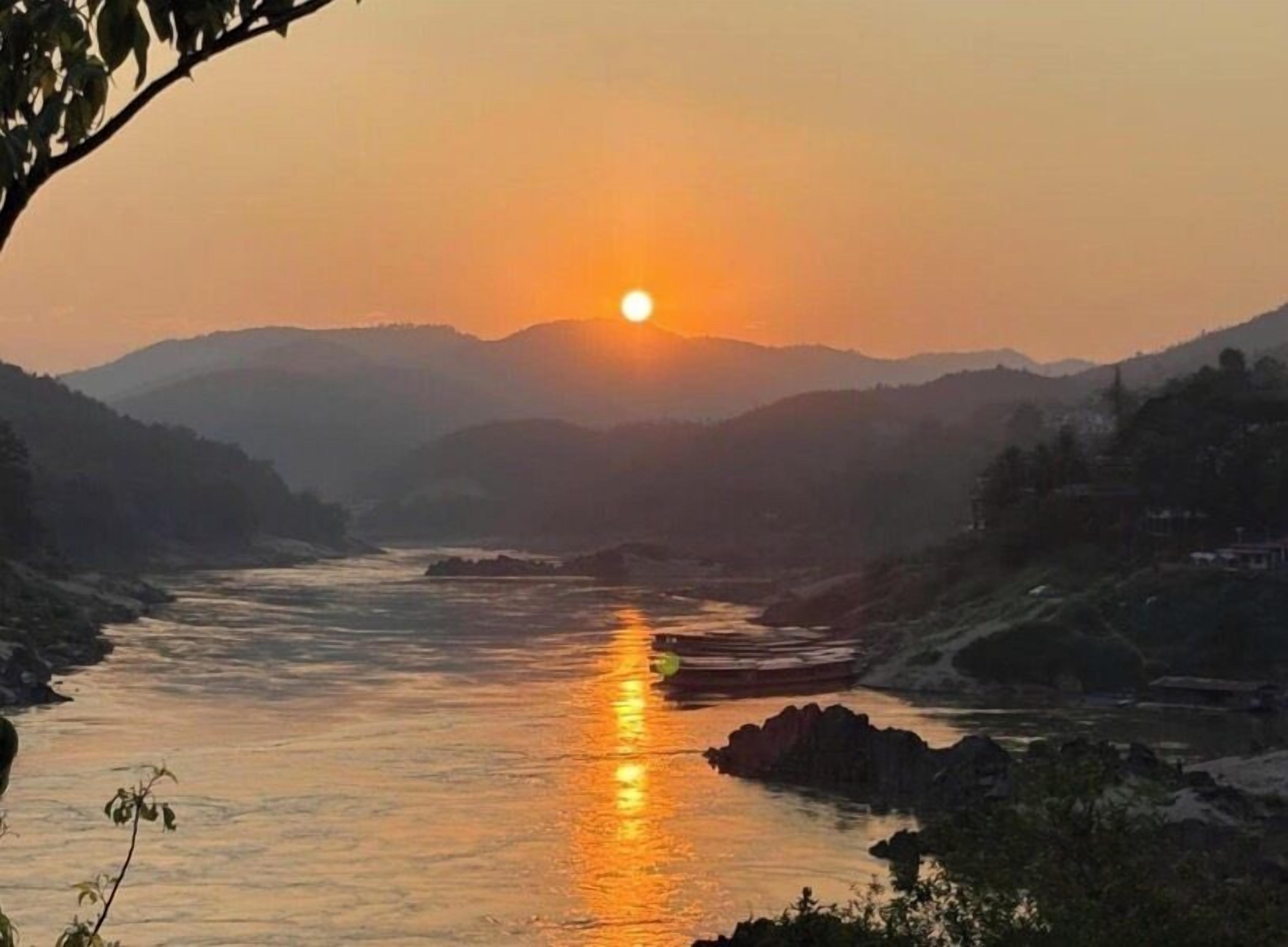 A sunset over a river with mountains in the background.