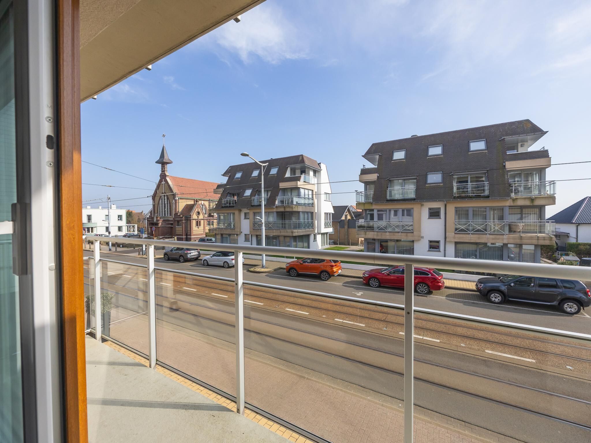 Ein Balkon mit Blick auf eine Straße, Gebäude und eine Kirche.