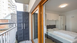 A modern bedroom with a bed, wardrobe, and a balcony. - Stylish apartment with terrace close to the sea (Middelkerke)