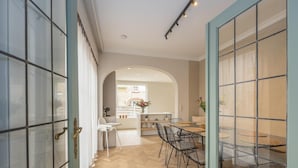 A modern interior with a dining area, kitchen, and a view through a glass door. - Luxury holiday home for 8 people near the sea (Westende)