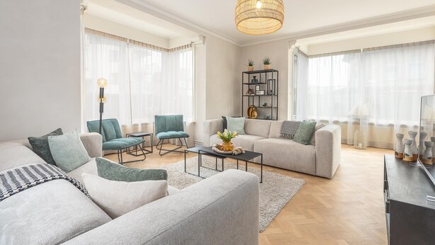 A modern living room with two sofas, a coffee table, and a bookshelf. - Luxury holiday home for 8 people near the sea (Westende)