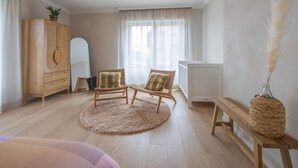 A room with two wicker chairs, a round rug, a wooden bench, a woven basket, and a tall vase with pampas grass. - Luxury holiday home for 8 people near the sea (Westende)