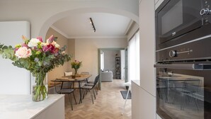 A modern kitchen with a built-in oven and a dining area with a table and chairs. - Luxury holiday home for 8 people near the sea (Westende)