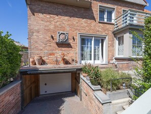 A brick house with a garage, a balcony, and potted plants. - Luxury holiday home for 8 people near the sea (Westende)