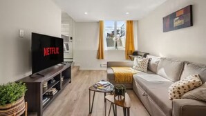 Ein modernes Wohnzimmer mit Flachbildfernseher, der "NETFLIX" zeigt, einer Couch, einem Couchtisch und einem Bücherregal.