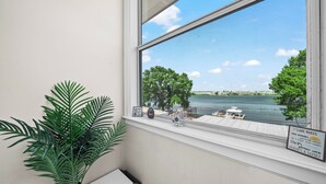 Ein Fenster mit Blick auf einen See, eine Bank und ein Schild.