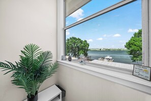 Une fenêtre donnant sur un lac, un banc et un panneau indicateur.