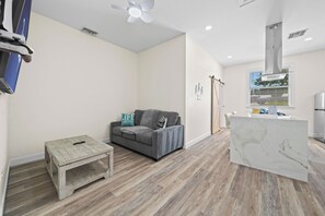 A modern living room with a grey sofa, a small wooden table, and a marble coffee table.