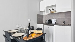 Cozinha compacta com mesa de jantar posta para quatro, geladeira, cafeteira e porta-facas.