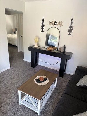 Ein Wohnzimmer mit einer Couch, einem Couchtisch, einem Kamin und einem Bett im Hintergrund.