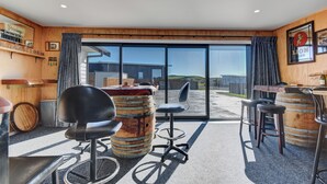 A modern bar area with wooden accents, a large window, and a view of the outside. - Family Home Away From Home (Waverley)