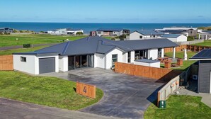 A modern house with a garage, a covered patio, and a view of the ocean. - Family Home Away From Home (Waverley)