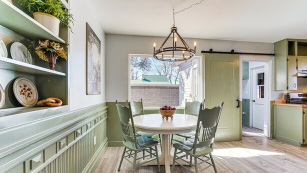 A dining area with a round table, four chairs, and a chandelier. There is a window with a view of a house and trees. - Group-Friendly Oasis Near Roper Lake State Park! (Safford)