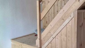 A wooden staircase with a handrail, a wooden ceiling, and a light fixture.