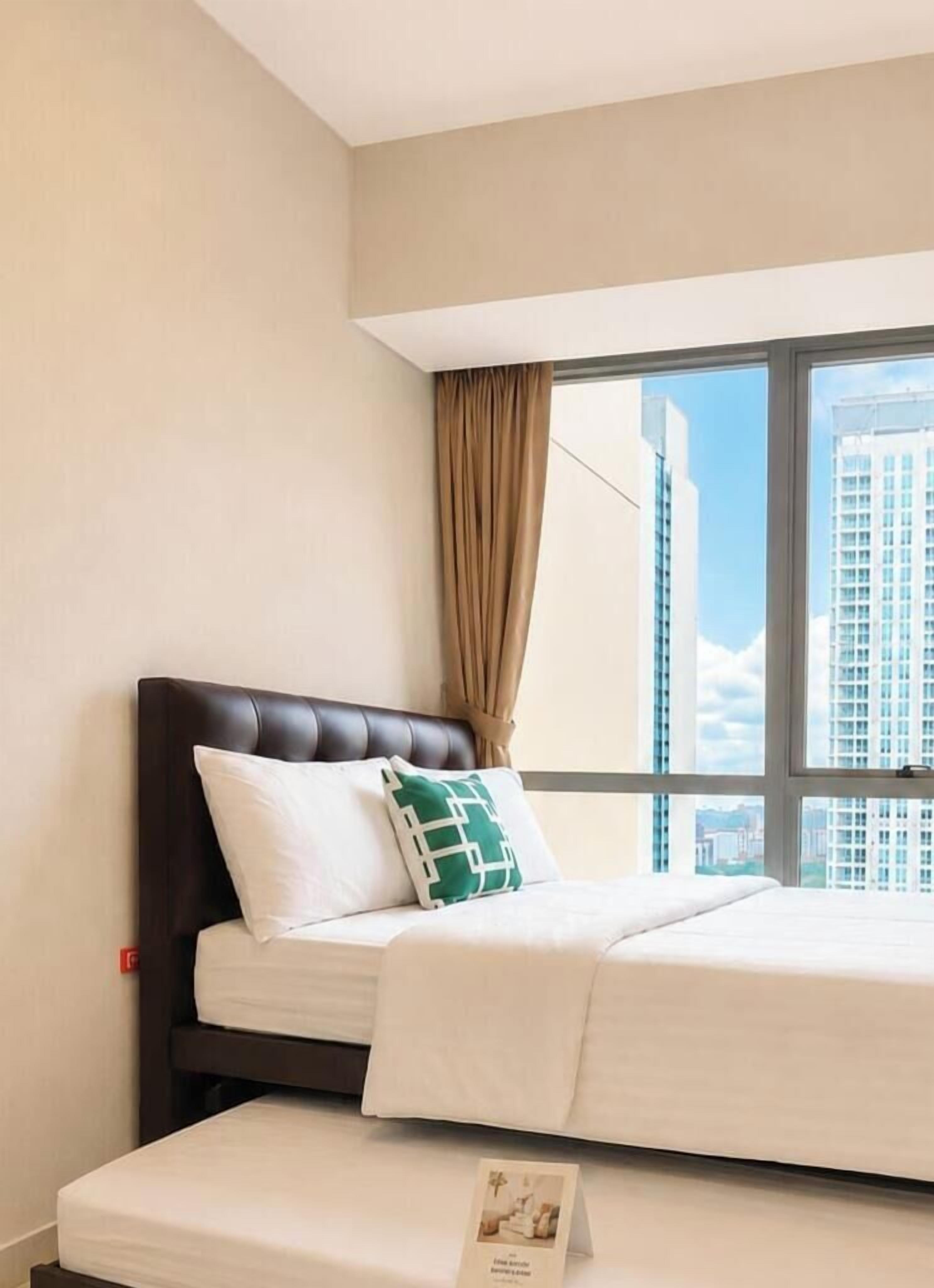Quarto de hotel com cama, janela com cortinas e vista para edifícios.