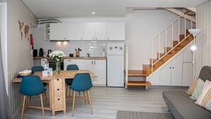A modern kitchen with white cabinets, a wooden dining table, and blue chairs.