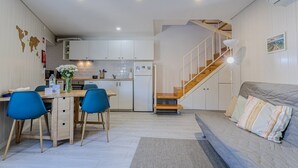 A compact living space with a kitchenette, dining area, and a staircase leading to an upper level.