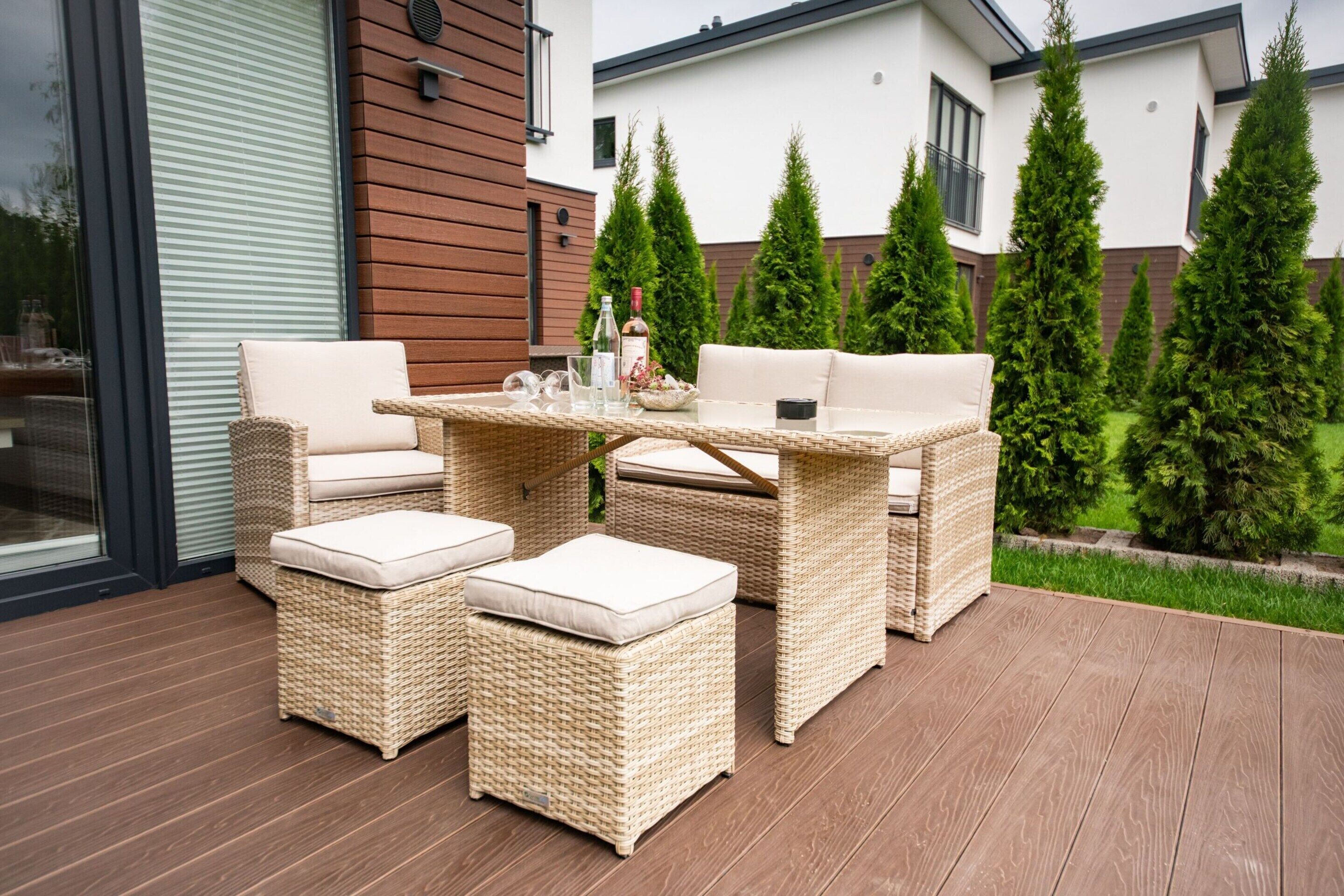 Un espace extérieur aménagé en terrasse, avec des meubles en osier, notamment une table et deux chaises, ainsi qu’un petit canapé.