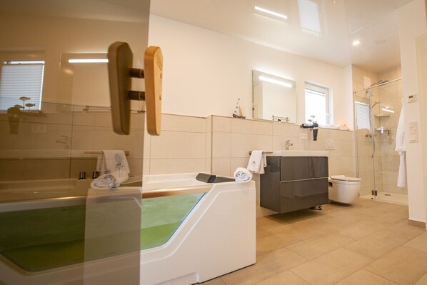 Un baño moderno con bañera, ducha, lavamanos e inodoro.