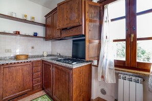 Eine Küche mit Holzausstattung, einer Granitarbeitsplatte, einem Herd und einem Fenster mit Vorhängen.