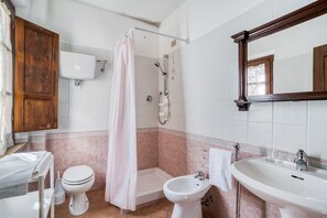 Ein Badezimmer mit Toilette, Bidet, Dusche und Waschbecken.