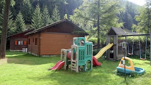A wooden cabin with a slide and play structure in a forested area. - Holiday Home in Nysted by Baltic Sea (Saas-Balen)
