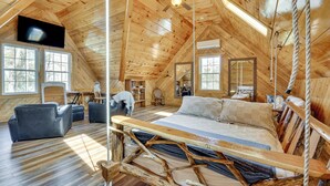 A wooden interior with a bed, sofas, a television, and a rope swing. - Steps to Private Beach! Family Home on Lake James (Nebo)