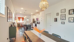 Una cocina moderna con armarios blancos, electrodomésticos de acero inoxidable y un comedor con una mesa de madera larga y sillas.