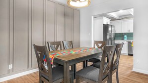 A dining area with a wooden table and chairs, a colorful table runner, and a pendant light.