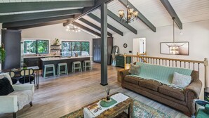A spacious living area with a large sofa, a coffee table, and a view of the kitchen and dining area. - Modern Forest Escape, Near Lake Stevens & Hikes (Lake Stevens)