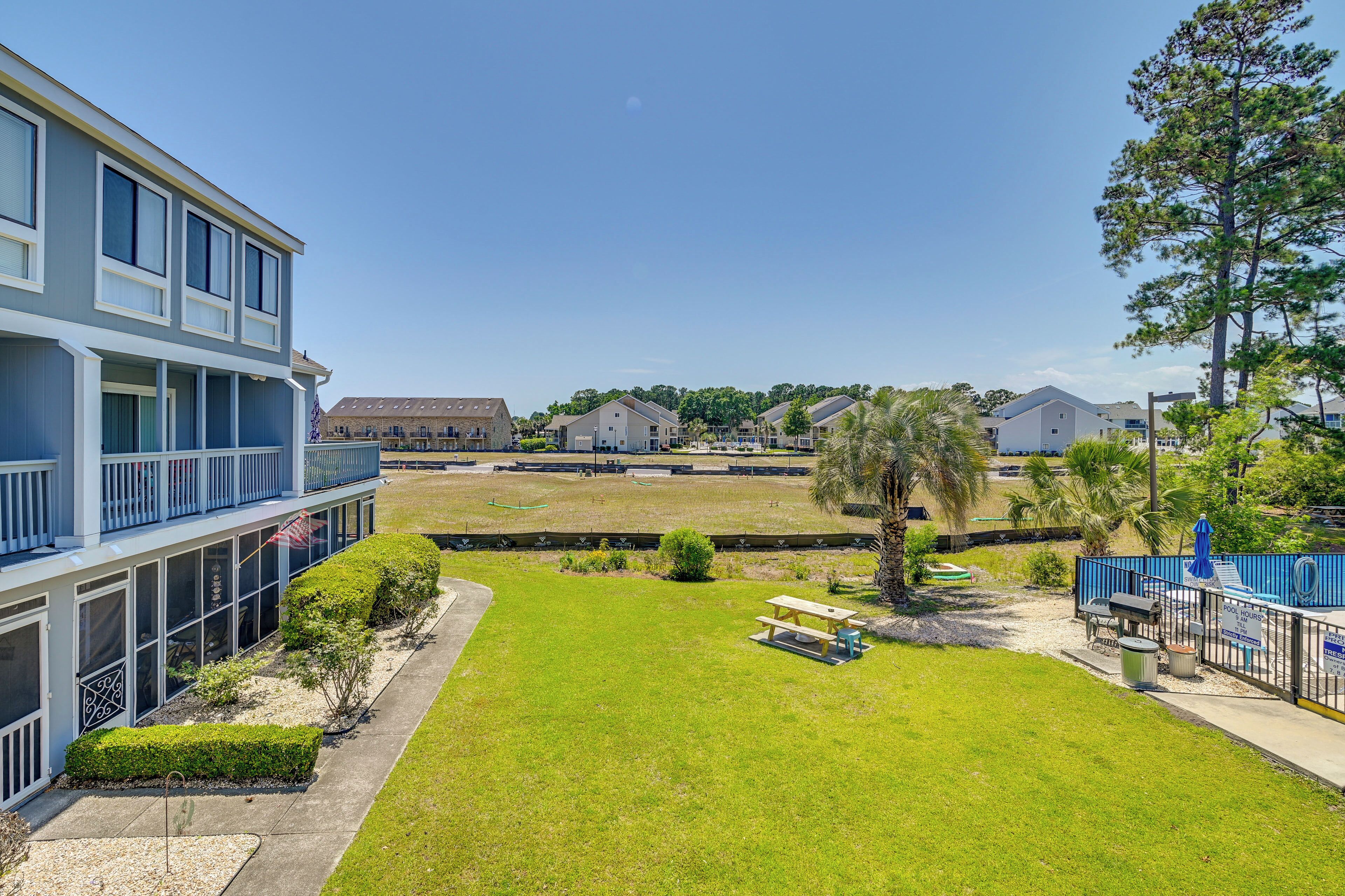 A residential area with a grassy lawn, picnic tables, and a swimming pool.