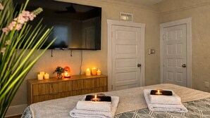 Ein Hotelzimmer mit einem Bett, einem an der Wand montierten Fernseher, einer Holzkommode und zwei Türen.