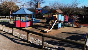 Un parque infantil con tobogán, estructuras para escalar y una zona de estar techada.