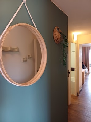 A hallway with a round mirror on the wall, a woven basket, and a potted plant. - Cap Esterel, sea view apartment with air conditioning, near swimming pool, padel and golf course (Saint-Raphaël)
