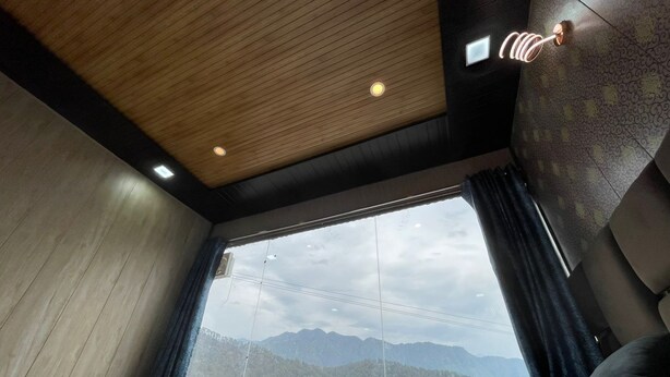 Una camera d'albergo moderna con un letto grande, vista sulle montagne e un soffitto in legno.