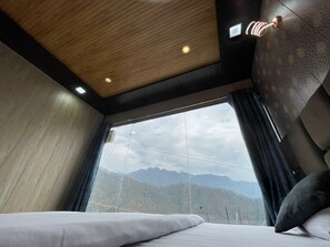 A modern hotel room with a large bed, a view of mountains, and a wooden ceiling. - Premji Hotel And Restaurant (Ukhimath)