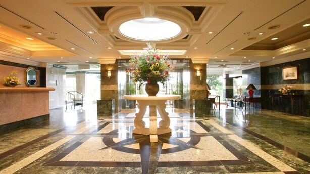 Un hall d'hôtel agrémenté d'une composition florale centrale, d'un comptoir de réception et d'un guichet d'enregistrement.