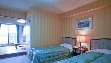 Habitación de hotel con dos camas, una mesita de noche con lámpara, un cuadro en la pared y una ventana con cortinas.
