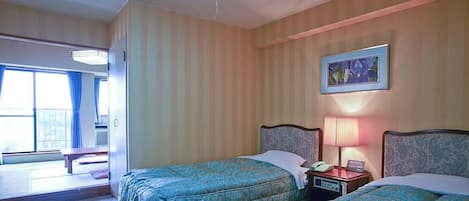 A hotel room with two beds, a bedside table with a lamp, a painting on the wall, and a window with curtains.