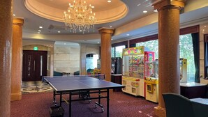 Une pièce spacieuse équipée d’une table de ping-pong, d’un lustre et de machines à pinces.