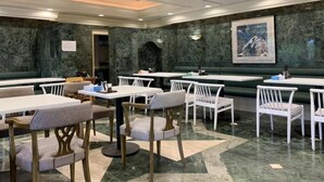 Un restaurant aux murs de marbre, aux meubles blancs et dont le plafond est agrémenté d’un éclairage encastré.